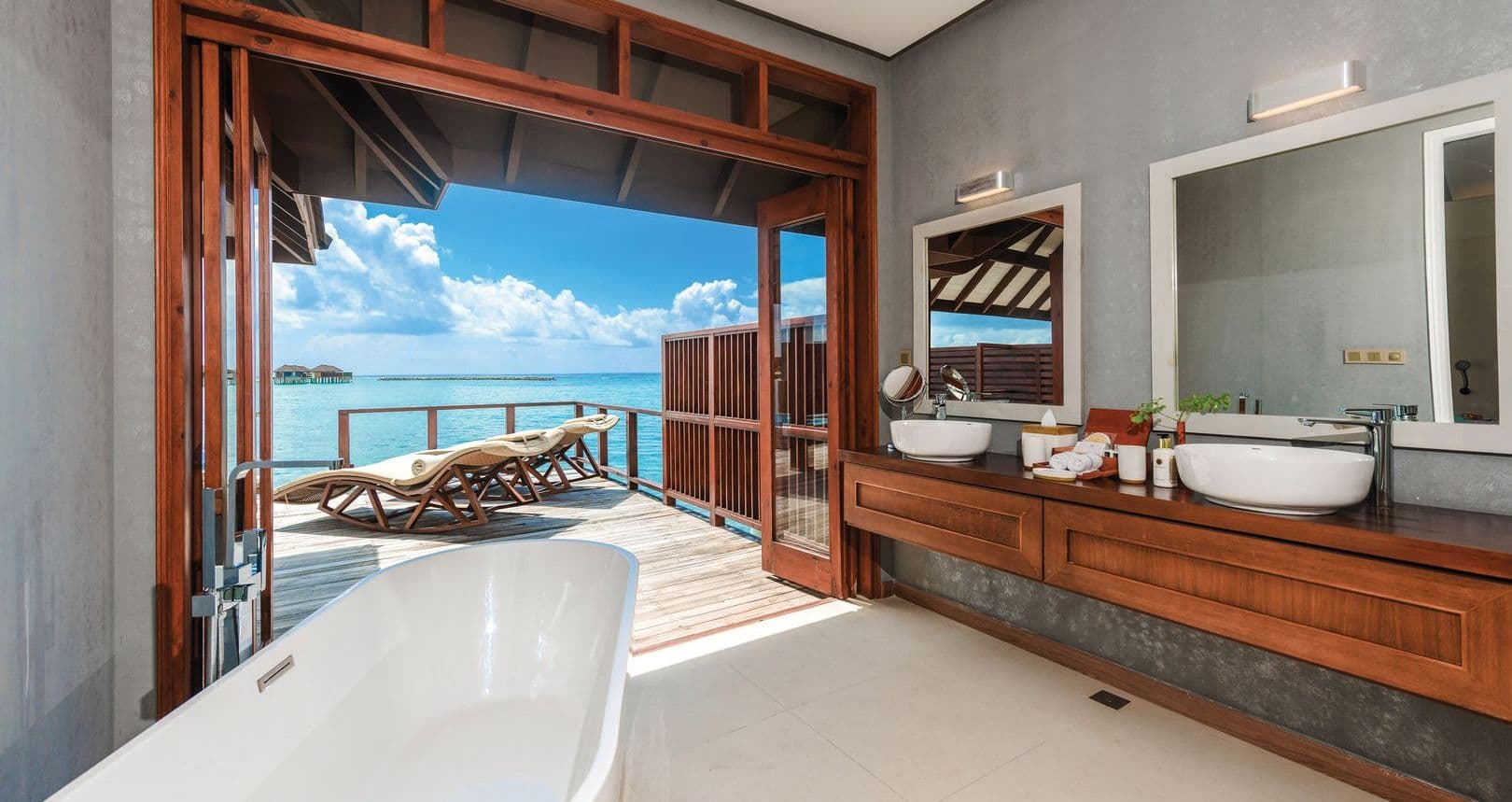 A bathroom with a bathtub and a bathtub on a deck overlooking the ocean.
